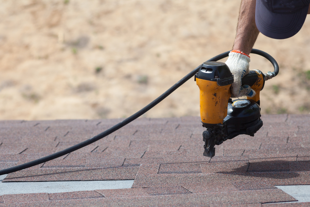 Worker using nail gun on roof