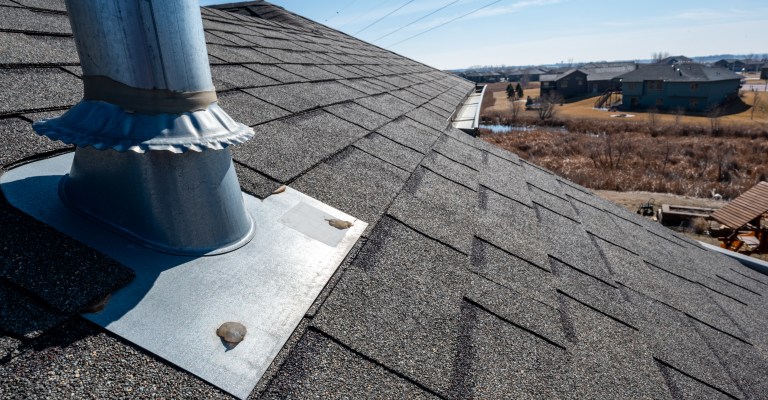 Vent on a shingle roof with silicon caulking and flashing for a water tight seal