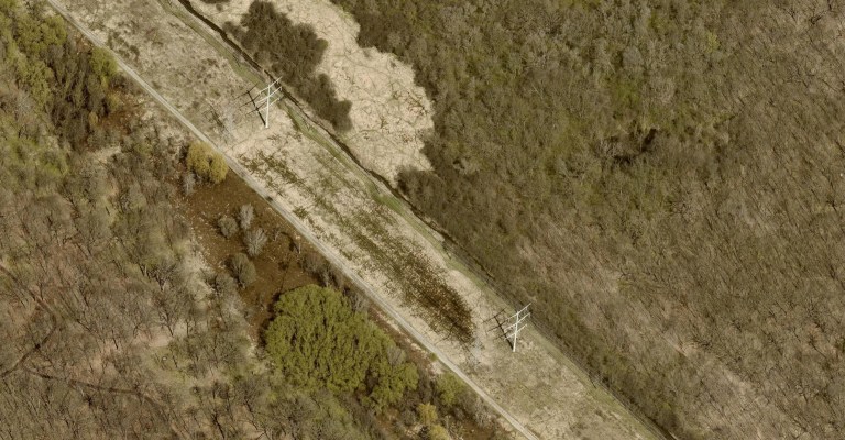 Aerial capture of a power line in a rural field.